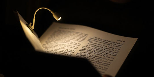 Clip-on book light illuminating a book page in dim lighting.